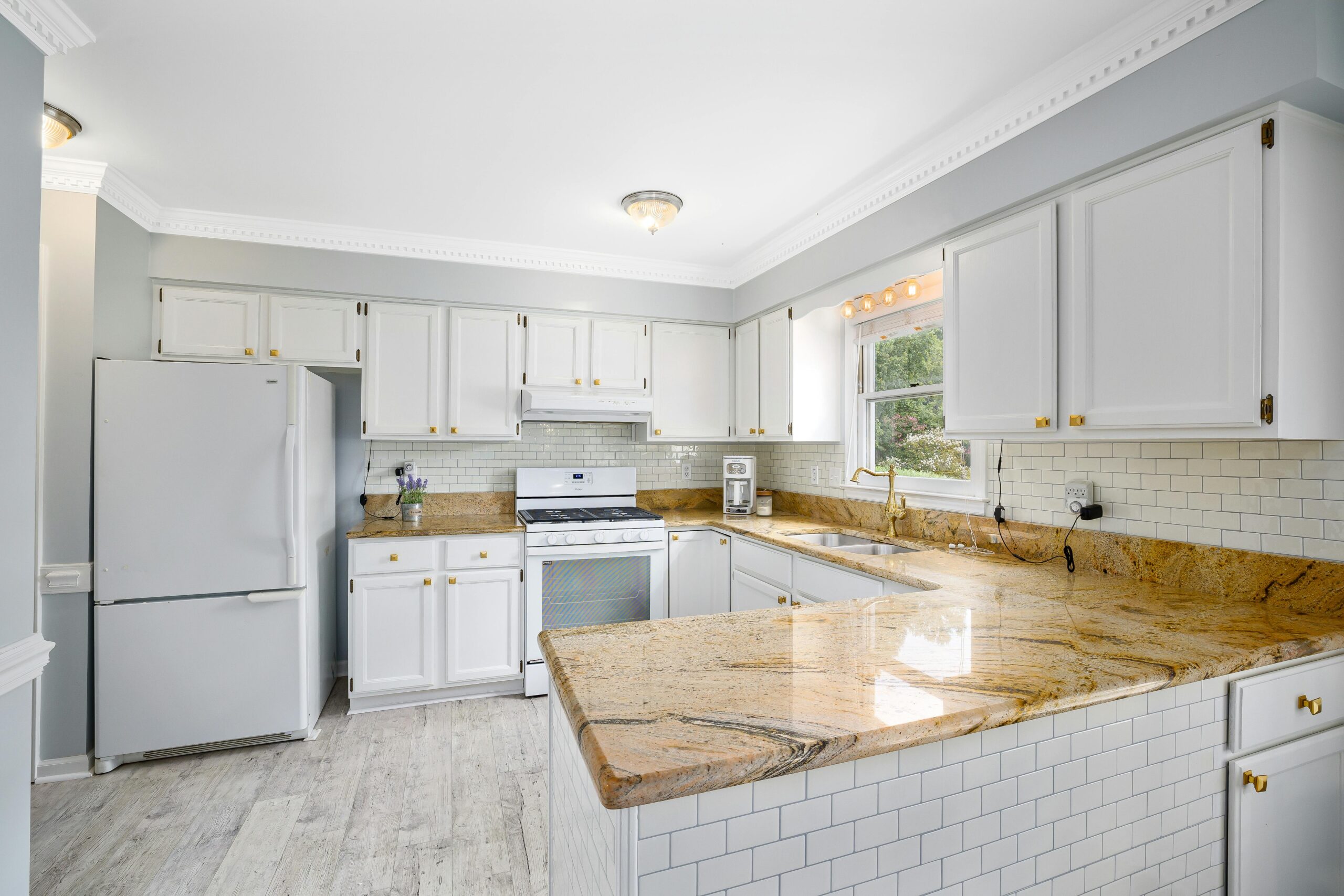 Bright Austin kitchen with white cabinets, granite countertops, subway tile backsplash, and hardwood floors